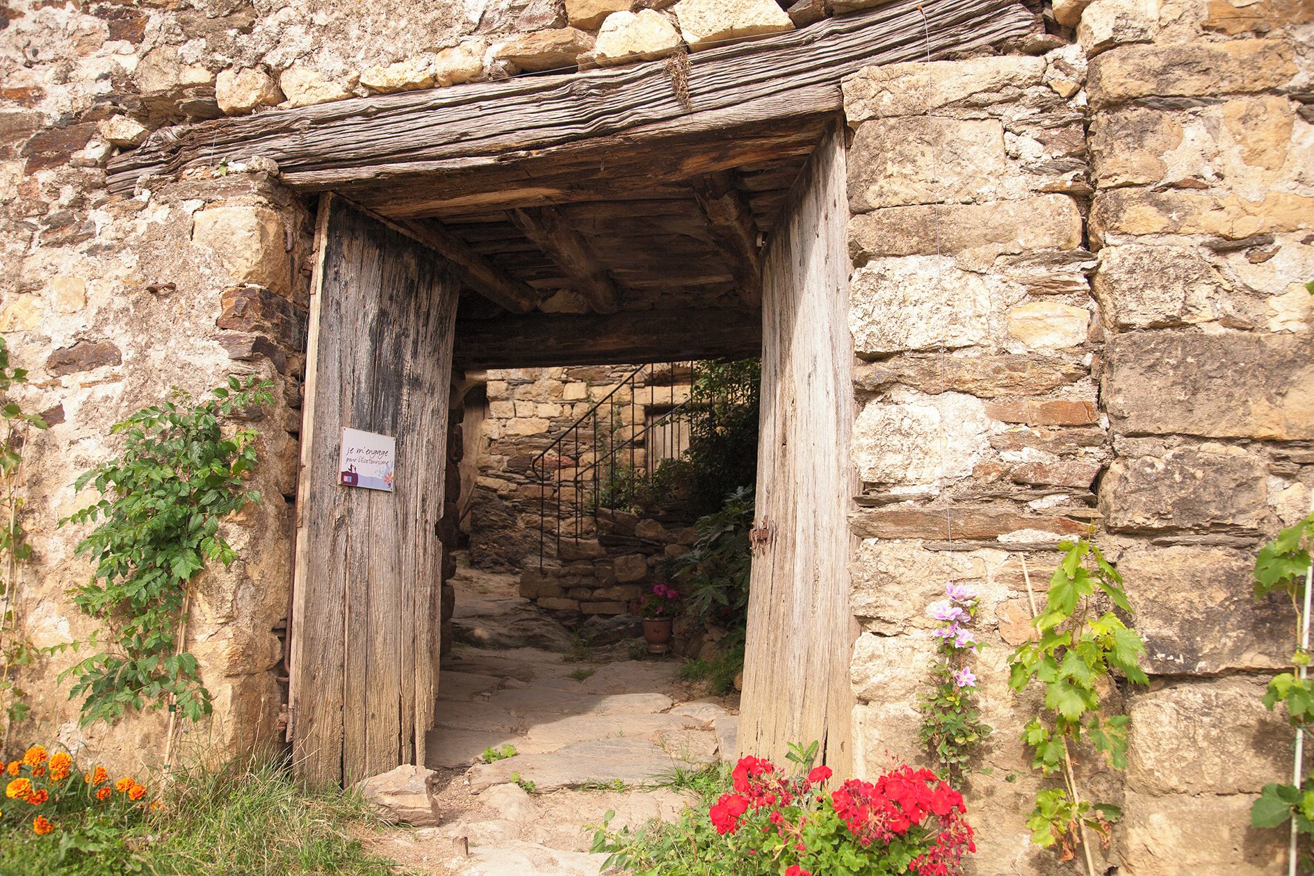 Una entrada a un edificio de piedra con una puerta de madera y un letrero en la pared.