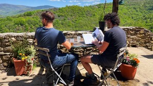 Two people seated at a table with a view of green hills and a clear sky. - La ferme des Cévennes (Florac)