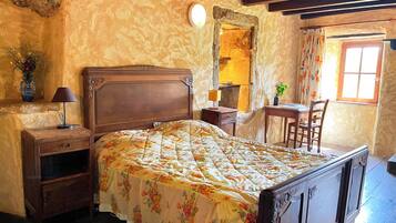 A bedroom with a wooden bed, a nightstand, a desk, and a chair.