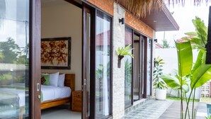 Un dormitorio con una cama, una mesita de noche de madera y un ventanal grande.