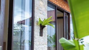 Fachada moderna de edificio con amplios ventanales, un pilar de piedra y una planta en maceta.