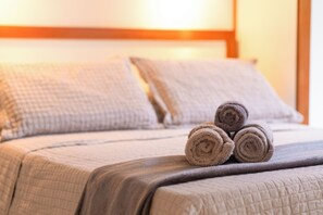 A neatly made bed with rolled towels and a quilted blanket.