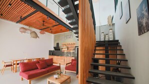 Un salon moderne avec un canapé rouge, une table basse en bois et un escalier doté de rampes noires.