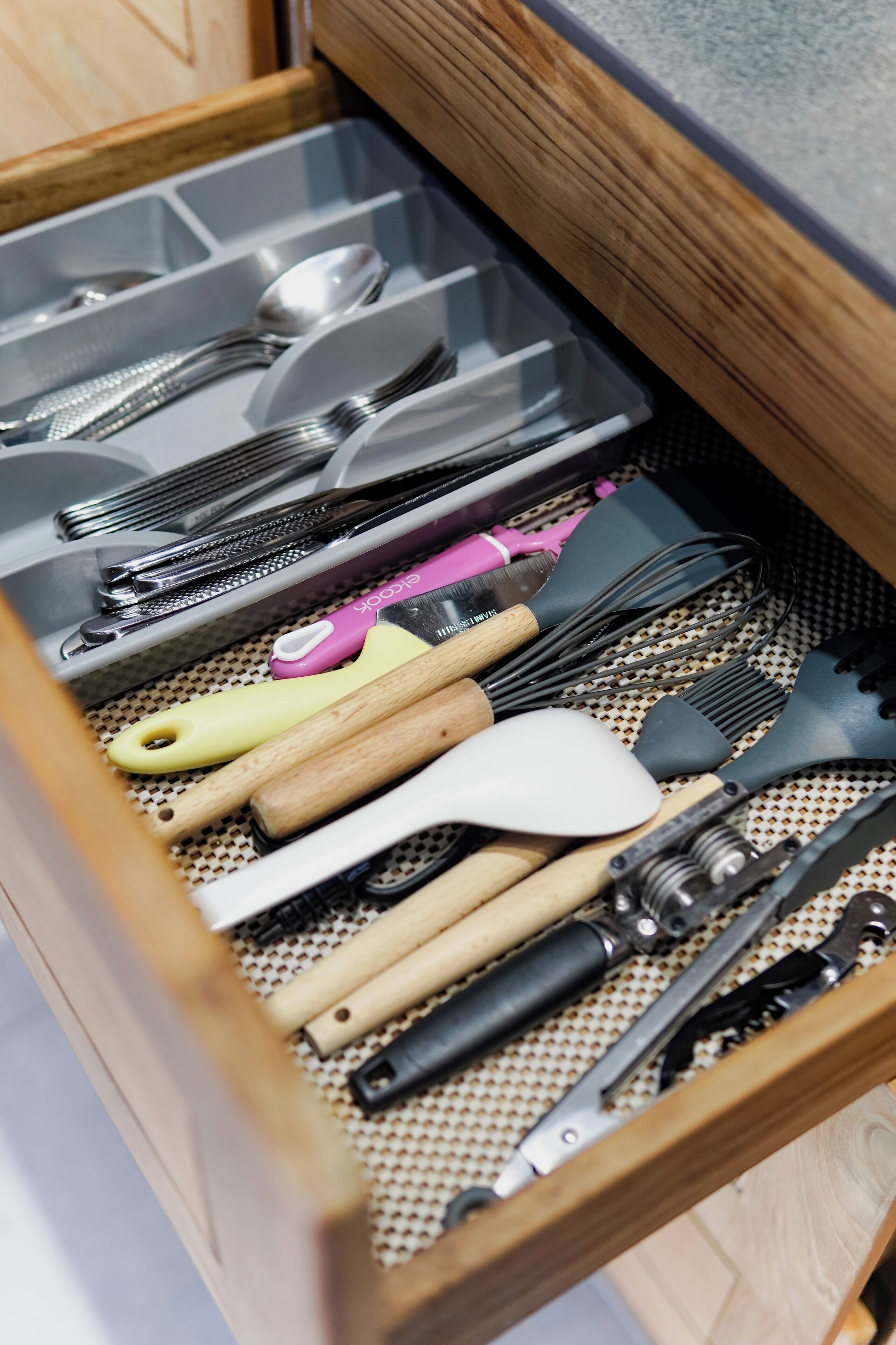 A drawer with various kitchen utensils including spoons, spatulas, and whisks.
