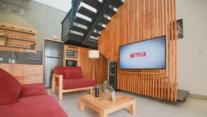 Un salon moderne avec un canapé rouge, une table basse en bois et un téléviseur affichant le logo « NETFLIX ».