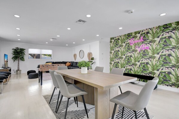 Un espace de salle à manger moderne avec une table en bois, des chaises grises et une grande plante.