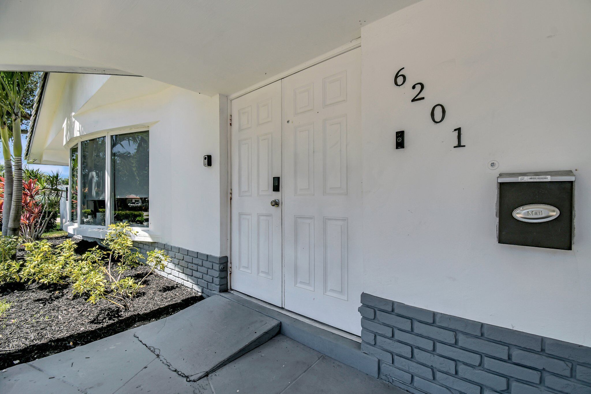 A white exterior with a mailbox and a door marked with the number 6201.