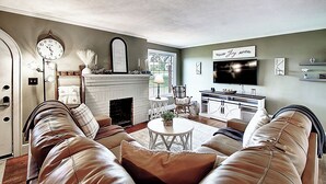 Ein Wohnzimmer mit Kamin, Ledersofas, einem Couchtisch und einem Fernseher.