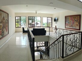Una habitación amplia con balcón, ventanas grandes y una escalera con barandilla ornamentada.