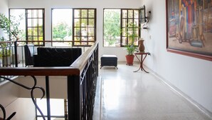 Ein geräumiges Zimmer mit Balkon, großen Fenstern und Deckenventilator.