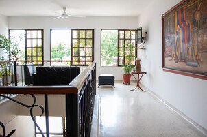 Una habitación amplia con balcón, ventanas grandes y ventilador de techo.