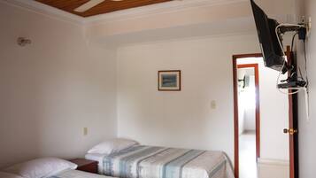 A bedroom with two beds, a ceiling fan, a television mounted on the wall, and a door leading to another room.