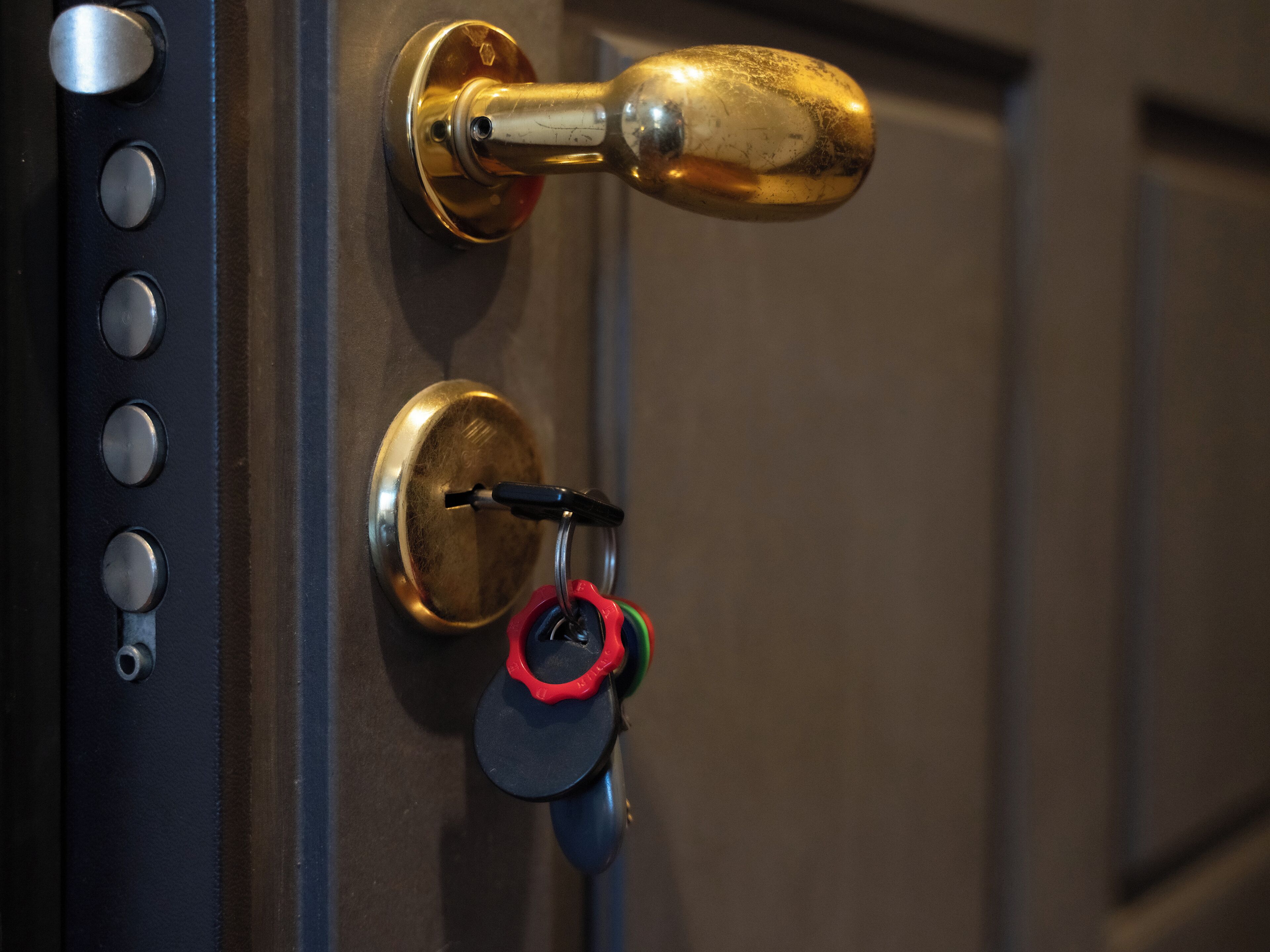 A door with a brass handle, a keyhole, and a keyring with a key.