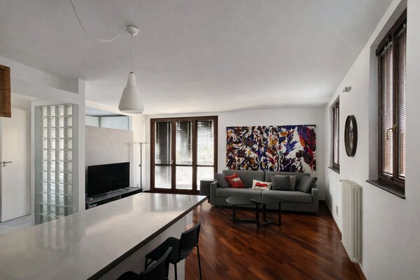 A modern living space with a kitchen area, a dining table, and a sofa.
