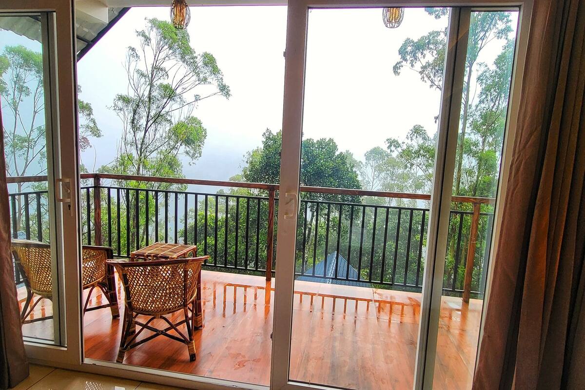 Ein Balkon mit Korbmöbeln und Blick auf ein bewaldetes Gebiet.