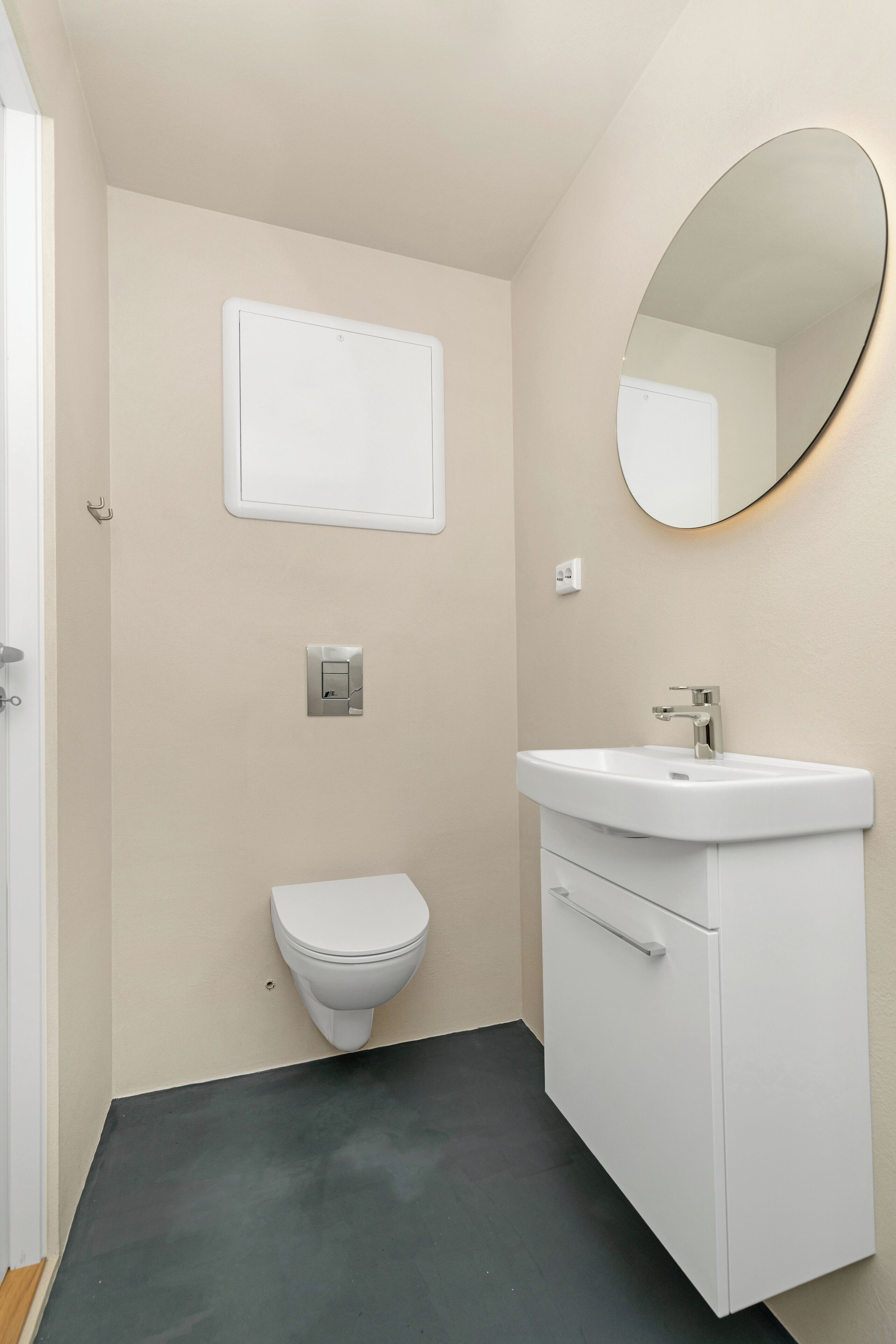 A bathroom with a toilet, a white sink, a mirror, and a light switch on the wall.