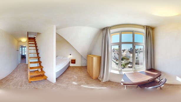 A spacious room with a curved ceiling, a wooden staircase, a bed, a small table, and a large window with curtains. - Central Guest House - Private Bathroom (Stavanger)