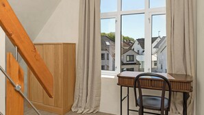 A room with a desk and chair, a window with curtains, a wooden cabinet, and a staircase. - Central Guest House - Private Bathroom (Stavanger)