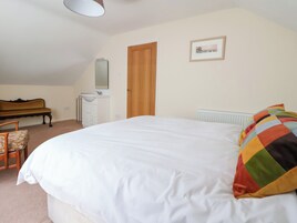 A bedroom with a large bed, a wooden bench, a small white dresser, and a radiator.