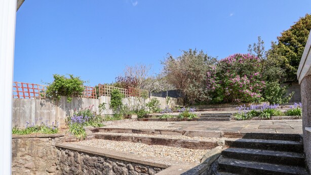 A stone staircase leading up to a garden with a wooden fence and flowering plants. - Bryn Bach (Colwyn Bay)