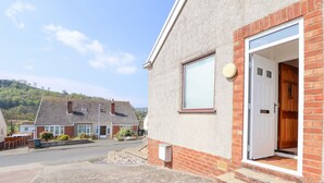 A residential building with a brick facade, a white door, and a small window. - Bryn Bach (Colwyn Bay)