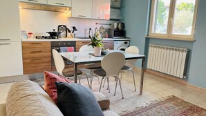 A modern kitchen with white cabinets, a dining table with chairs, and a window with a view of greenery. - "Home from Home" with outdoor spaces for eating and relaxing, 5 minutes from the sea. (Tortoreto)