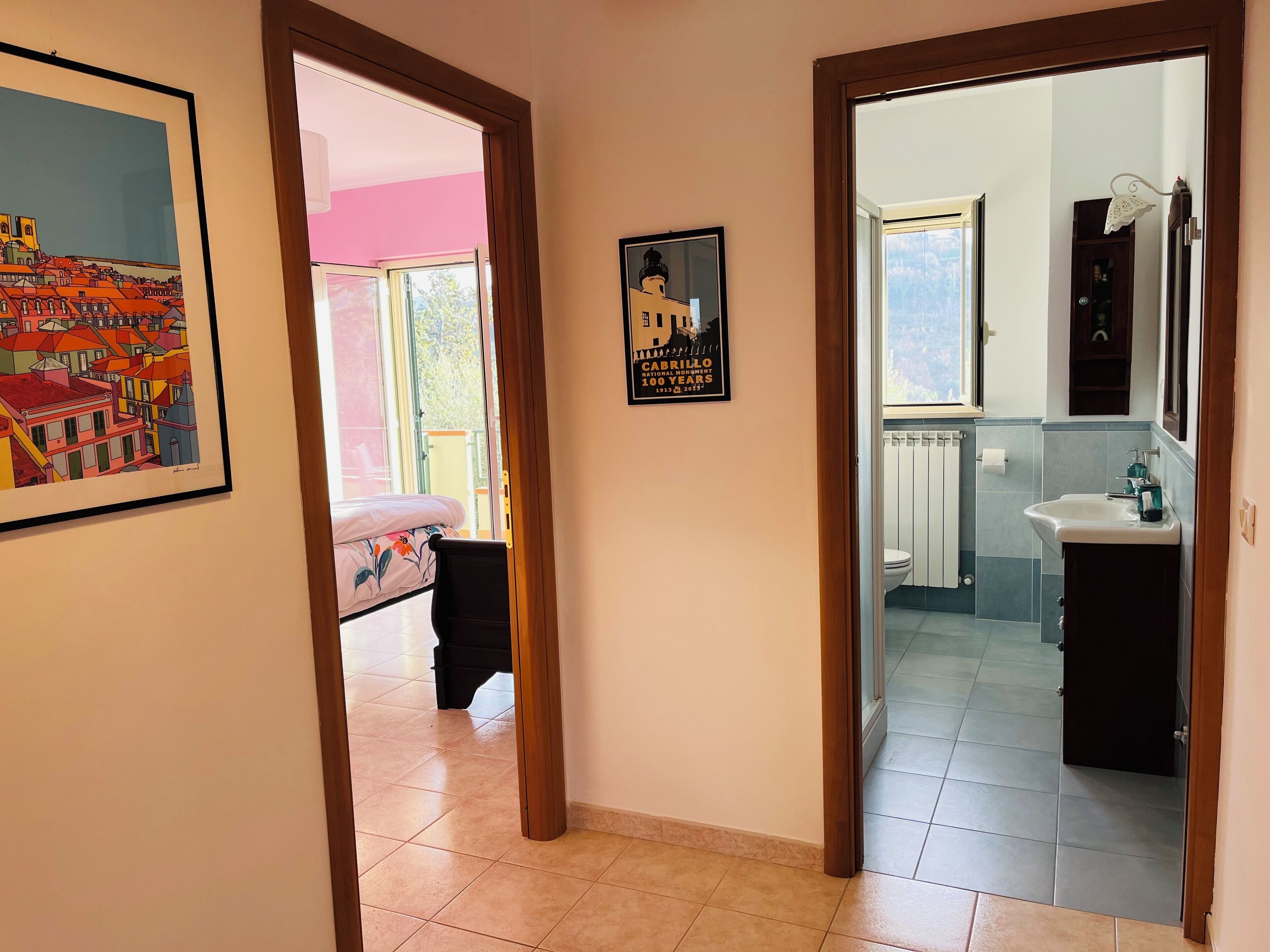 A hallway with a bed, a framed picture, and a poster.