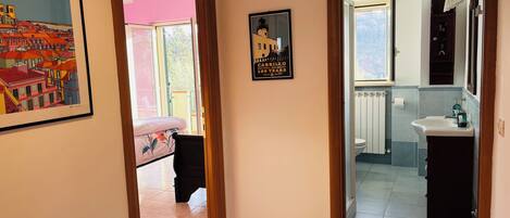 A hallway with a bed, a framed picture, and a poster.