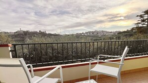 A balcony with white chairs and a table, overlooking a cityscape with buildings and greenery. - "Home from Home" with outdoor spaces for eating and relaxing, 5 minutes from the sea. (Tortoreto)