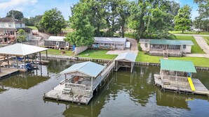Une propriété située au bord de l’eau, avec des bateaux amarrés, un hangar à bateaux couvert et un petit bâtiment doté d’un porche.