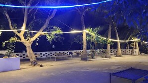 Un espace extérieur agrémenté d’arbres, de bancs et de guirlandes lumineuses.