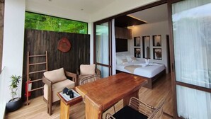 A modern room with a wooden table, chairs, a bed, and a ceiling fan.