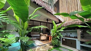 A modern outdoor living area with a pool, stone steps, and tropical plants.