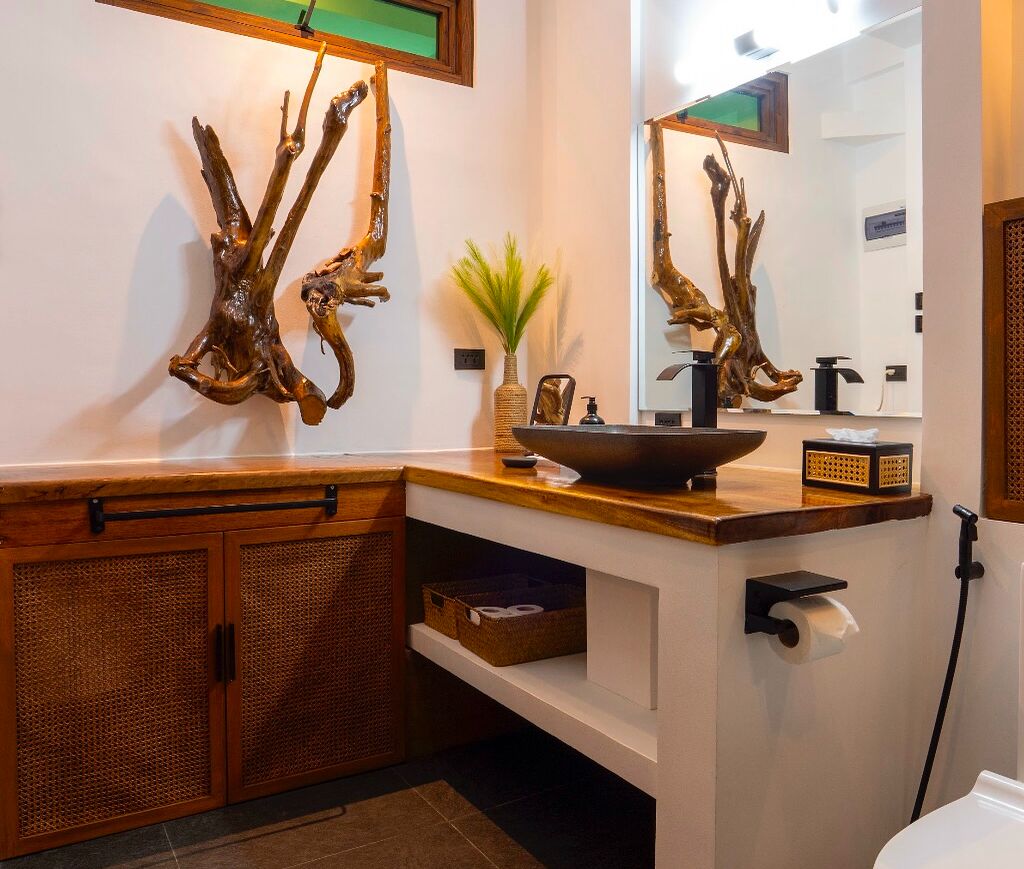 A bathroom with a wooden vanity, a sink with a bowl, a mirror, and a decorative plant.