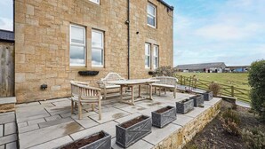 A stone building with a patio area featuring outdoor furniture and planters. - Mount Cottage, 5-beds, Sleeps 10, Pet Friendly (Newcastle-upon-Tyne)