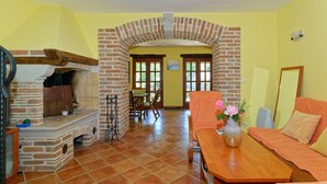 Un salon avec une cheminée en briques, des murs jaunes, une table à manger en bois et un canapé.