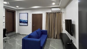 Un salon moderne avec un canapé bleu, un téléviseur à écran plat et un climatiseur fixé au mur.