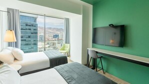 Habitació d'hotel amb una finestra gran, un llit, un escriptori i una televisió.