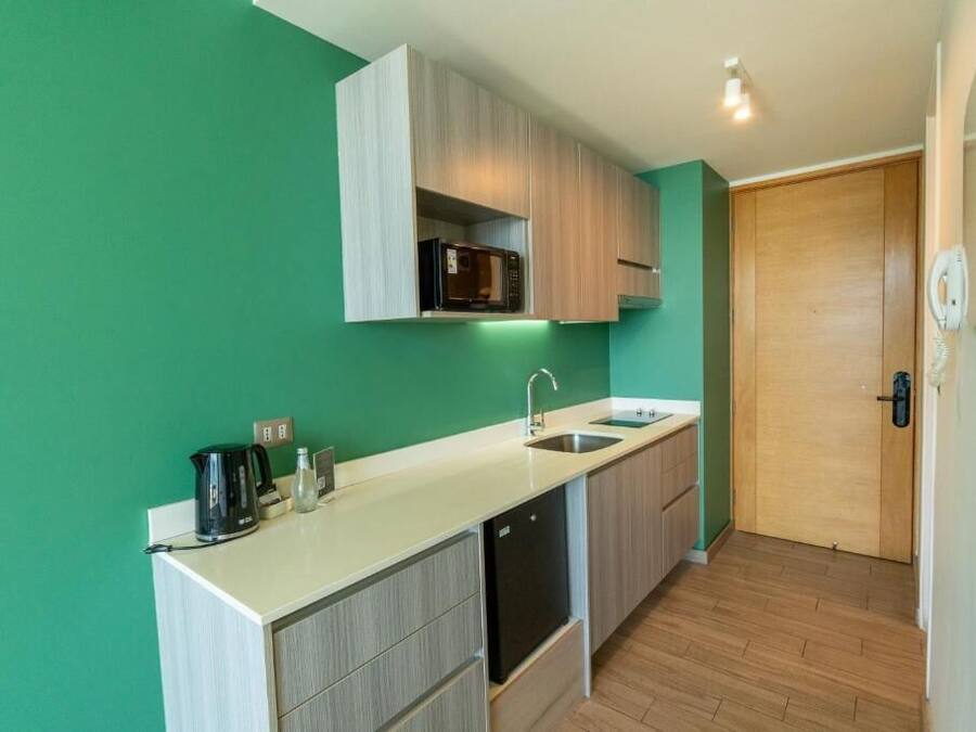 A compact kitchen with a microwave, sink, and cabinets.