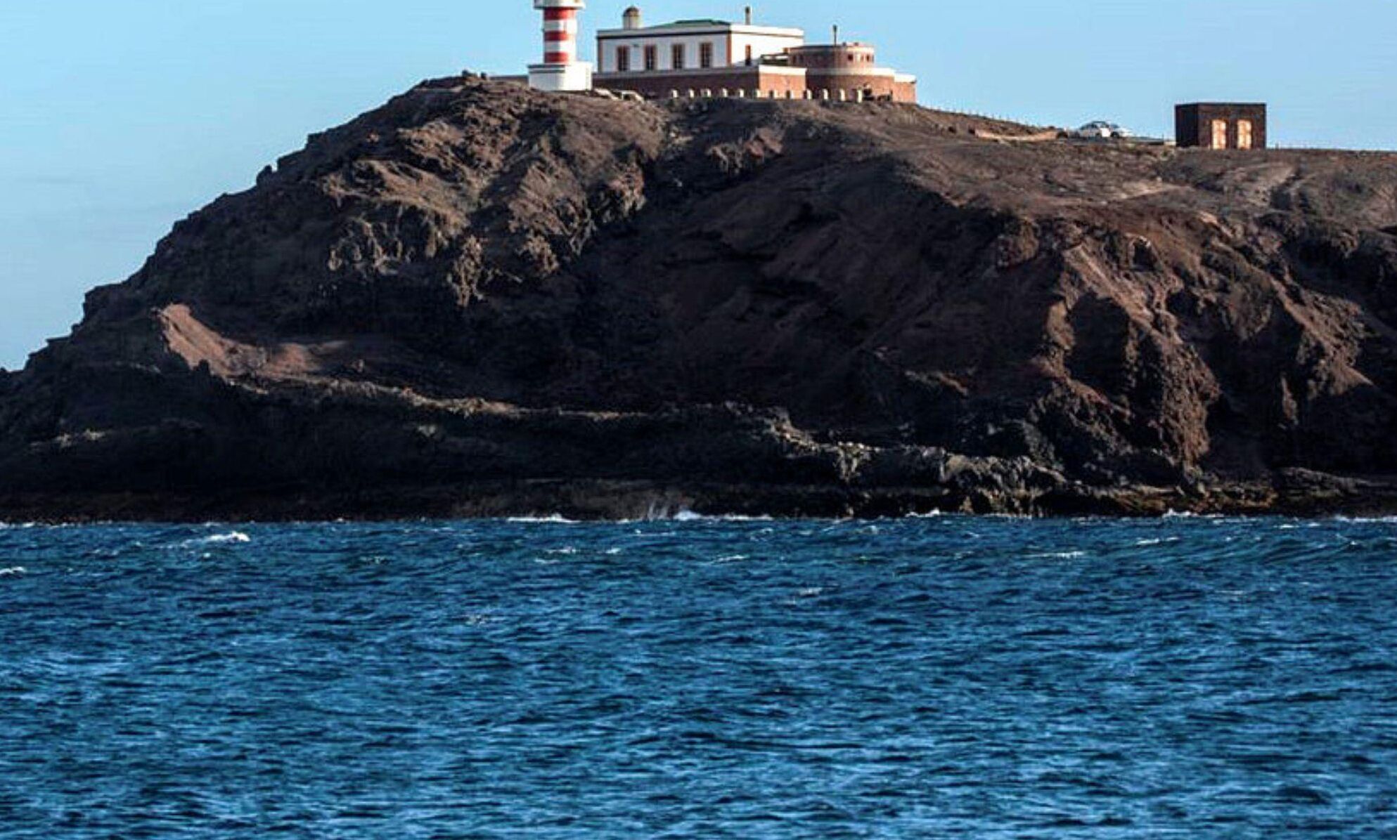 Une île rocheuse avec un phare et des bâtiments.