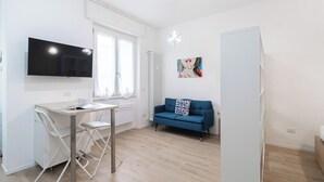 A modern apartment with a flat-screen TV, a blue sofa, a dining table, and a radiator. - Italianway - Cambiasi 8 (Milan)