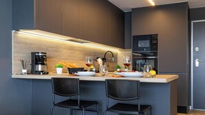 Una cocina moderna con armarios oscuros, encimera de madera y dos taburetes negros.