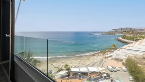 Un balcón con vista al mar, la playa y un complejo de edificios.