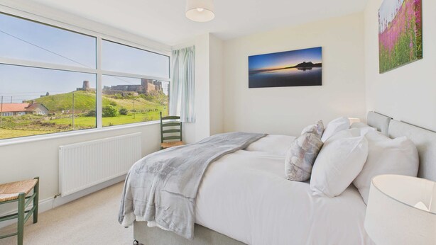 Une chambre avec une grande fenêtre, un lit, une chaise et un radiateur.