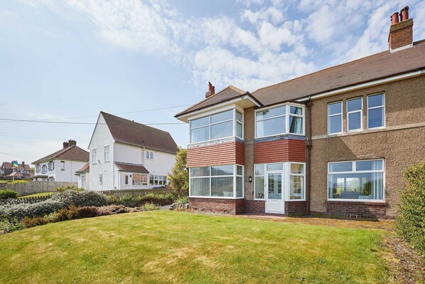 A two-story house with a large front lawn and a brick facade. - Host Stay Chirnells (Bamburgh)