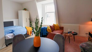 Une pièce de taille modeste comprenant un lit, un canapé, une petite table et une chaise.
