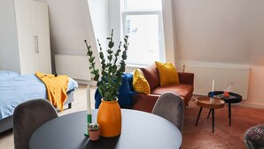 Une pièce moderne et bien éclairée, comprenant un lit, un canapé, une table à manger et une petite plante.