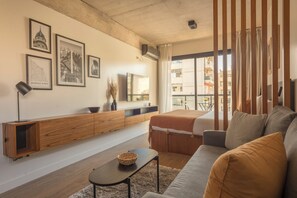 Relax in this stylish living room with a large window offering a view, a flat-screen TV, and a comfortable sofa.