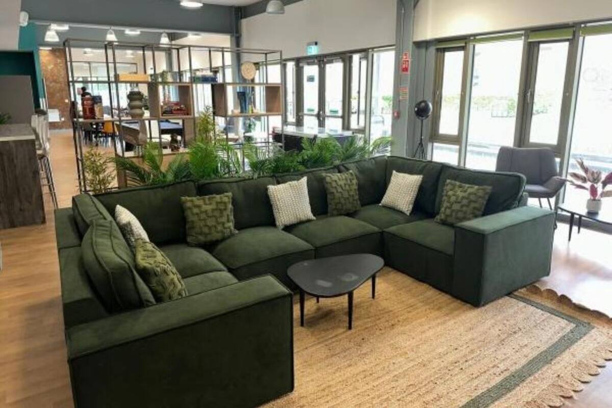 A modern interior with a sectional sofa, a small table, and large windows.