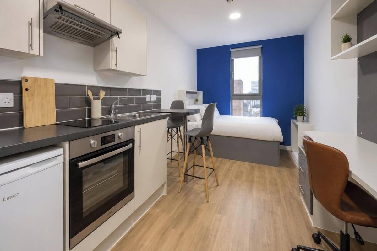A compact kitchen with a dishwasher, oven, and a dining area with stools.